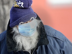A man wearing a mask walks along a sidewalk in Winnipeg on Friday, Nov. 27.