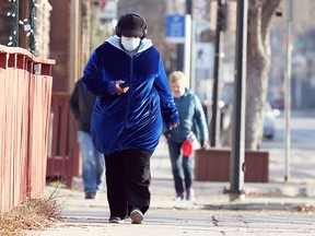 A woman wearing a mask walks on Corydon Avenue in Winnipeg on Nov. 4, 2020.