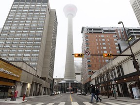 Two masked pedestrians cross the Centre Street in an almost empty downtown Calgary on a foggy morning before the holiday season on Friday, Dec. 11, 2020.