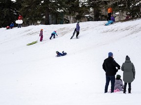 People spend the Christmas afternoon tobogganing down the hill in Confederation Park on Friday, Dec. 25, 2020.