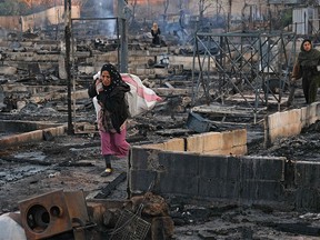 Syrian refugees salvage belongings from the wreckage of their shelters at a camp set on fire overnight in the northern Lebanese town of Bhanine on Dec. 27, 2020, following a fight between members of the camp and a local Lebanese family. - The United Nations refugee agency, UNHCR, confirmed a large fire had broken out in a camp in the Miniyeh region and said some injured had been taken to hospital, but did not provide an exact number.