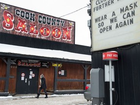 A woman walks past the closed Cook County Saloon, in Edmonton, on Nov. 24.