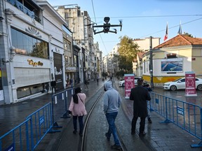 A Turkish police drone announce social distancing rules in English via a speaker, as people walk in Istiklal avenue in Istanbul during a week-end curfew aimed at curbing the spread of the Covid-19 pandemic caused by the novel coronavirus, December 5, 2020. - Under the new restrictions beginning from December 8, a curfew will be imposed on weekdays from 9:00 pm. to 5:00 am. Over the weekend the lockdown will last from 9:00 pm Friday until 5:00 am on Monday.