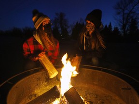 Friends Lindsay Kraus and Jessica McKenzie enjoy the firepit at the Collingwood Off-Leash Park as the city has placed them throughout parks in Calgary on Thursday, December 3, 2020.