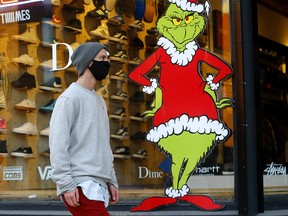 Tania walks by a store window on 11 Street and 14 Avenue S.W. as COVID cases remain high in Calgary on Thursday, December 17, 2020.