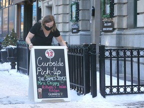 Jordan McCaffrey, manager of the James Joyce on Stephen Avenue mall, sets up a sign advertising curb-side service on Tuesday, Dec. 29, 2020.