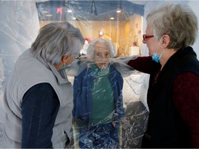 Marie-Paule and Marie-Josephe interact with their mother Colette, 97 old, behind a removable plastic sheet inside a bubble structure which allows families to give hugs without risk of contamination or transmission of Covid-19, installed in the refectory of the Residence du Carre d'Or retirement home at Jeumont Hospital as the coronavirus disease outbreak continues in France, December 4, 2020.