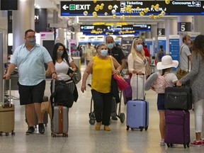 Travelers wearing protective face masks walking through Concourse D at the Miami International Airport on Sunday, Nov. 22, 2020, in Miami, Fla.
