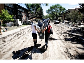 Volunteers carry a load of shovels and brooms donated in the flood-stricken Mission area, near the Elbow River, in Calgary in 2013. We've done it before, we can do it again, says columnist Preston Manning. Let's stick together.