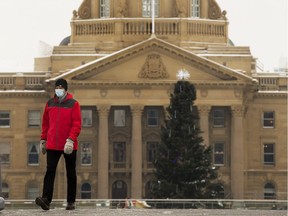 A pedestrian wearing a mask to protect against COVID-19 walks past the Alberta Legislature, in Edmonton Monday Nov. 23, 2020.