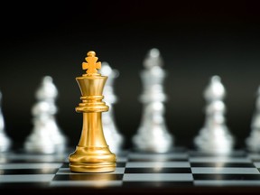 Gold king in chess game face with the another silver team on black background (Concept for company strategy, business victory or decision)