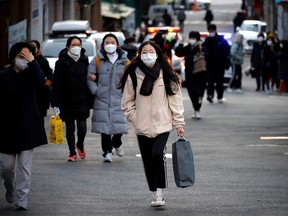 Students and family members walk in front of an exam hall ahead of the annual college entrance examinations amid the COVID-19 pandemic, in Seoul, South Korea, Dec. 3, 2020.