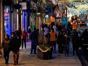 Pedestrians, some wearing a face mask or covering due to the COVID-19 pandemic, walk past shops closed due to the new Tier 4 coronavirus restrictions, on Regent Street in central London on December 20, 2020.