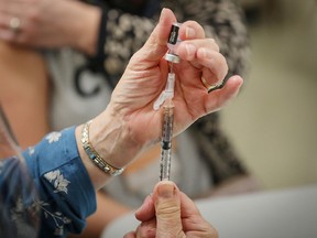 Lois Edey, a registered nurse in Calgary, prepares a COVID-19 vaccine for a health-care worker on Dec. 15, 2020.