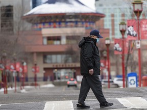 A masked pedestrian walks in Calgary’s Chinatown on Tuesday, Jan. 12, 2021.