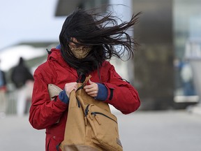 People traverse the overpass bridge at Crowfoot LRT Station while an extreme wind blows in Calgary on Wednesday, Jan. 13, 2021.