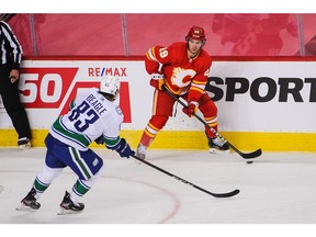 The Calgary Flames’ Dillon Dube carries the puck against the Vancouver Canucks’ Jay Beagle at the Scotiabank Saddledome  in Calgary on Jan. 16, 2021.