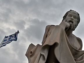 A statue of the ancient Greek philosopher Socrates stands in front of a Greek flag in Athens on June 27, 2015. In her exploration of happiness, columnist Catherine Ford wonders if Socrates had the answers.