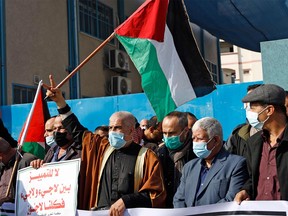 Palestinians wearing protective masks due to the COVID-19 pandemic, take part in a rally to protest a reported reduction of the food basket provided by the United Nations Relief and Works Agency for Palestine Refugees in the Near East (UNRWA), in front of the agency's headquarters at the Jabalia camp for Palestinian refugees in the northern Gaza Strip, on Dec. 23, 2020.