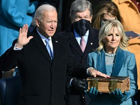 Joe Biden, flanked by incoming U.S. First Lady Jill Biden takes the oath of office as the 46th US President by Supreme Court Chief Justice John Roberts during the swearing-in ceremony of the 46th US President on Jan. 20, 2021, at the US Capitol in Washington, DC.