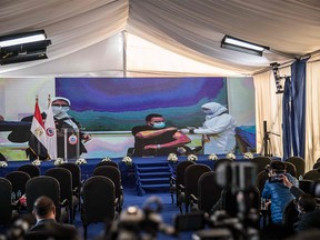 Journalists who are present for a press conference to be held  in a tent set up outside the Abou Khalifa hospital, are shown on a large screen the first Egyptian doctor, Abdelmounim Selem, as he is inoculate against the COVID-19, in Ismailia, about 120 km east the capital Cairo, on Jan. 24, 2021.