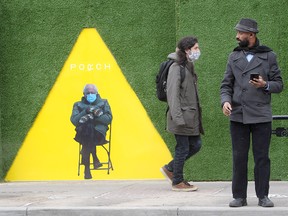 People walk past the Sen. Bernie Sanders mitten meme on 17th Avenue S.W. Monday, Jan. 25, 2021. Woollen mittens like the ones Sanders made famous could come in handy over the next 24 hours, as the city is expecting 10 to 15 centimetres of snow.