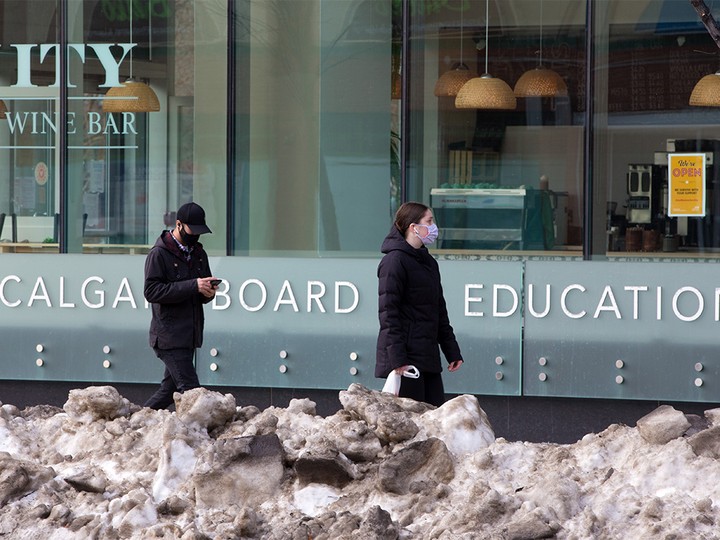  Masked pedestrians pass by the Calgary Board of Education building on Tuesday, Jan. 12, 2021.