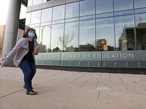 Masked pedestrians pass by the Calgary Board of Education building on Tuesday, Jan. 12, 2021.