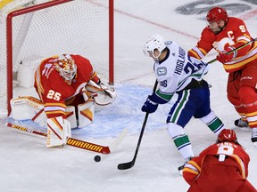 Calgary Flames goaltender Jacob Markstrom clears the puck in front of Vancouver Canucks forward Nils Hoglander and Flames defensemen Mark Giordano during the Calgary Flames NHL home opener on Saturday, January 16, 2021. 
Gavin Young/Postmedia