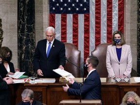 U.S. Vice President Mike Pence hands the West Virginia certification to staff as Speaker of the House Nancy Pelosi listens during a joint session of Congress after working through the night, at the Capitol in Washington, U.S., January 7, 2021.