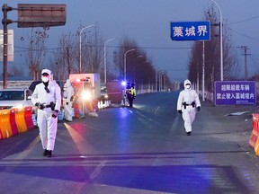Police officers and crews in protective suits inspect vehicles at a checkpoint on the borders of Gaocheng district on a provincial highway, following a COVID-19 outbreak in Hebei province, China, on Jan. 5, 2021.