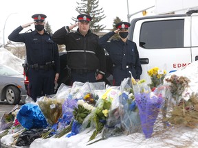Edmonton police officers pay their respects after taking part in a parade around Falconridge. Flowers mark the location where Sgt. Andrew Harnett was killed.