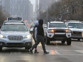A couple cross at Centre St. and 7 Ave. N on Wednesday, Jan. 27, 2021. Calgary has seen two fatal pedestrian collisions since the start of the year.