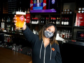 Karen Gott, assistant general manager of Trolley 5 Restaurant and Brewery in Calgary, raises a glass Friday after the province announced it will allow in-person dining on Feb. 8, 2021.
