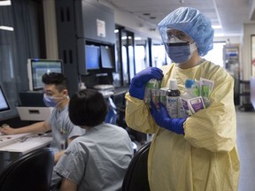 Registered nurse Cayli Hunt puts brings supplies into a COVID positive room in the COVID-19 intensive care unit at St. Paul's hospital in downtown Vancouver, Tuesday, April 21, 2020.