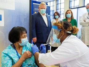 Ontario Premier Doug Ford and Deputy Premier of Ontario and Minister of Health Christine Elliott watch as a healthcare worker administers the second dose of the Pfizer-BioNTech coronavirus disease (COVID-19) vaccine to personal support worker Anita Quidangen, who is the first person in Ontario to receive both doses, at The Michener Institute, in Toronto, Canada January 4, 2021.