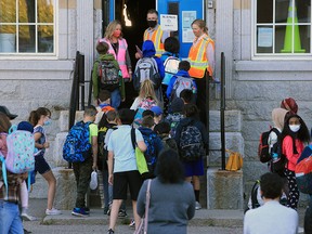 Staff lead students into class at a Calgary elementary school on Sept. 1, 2020.