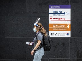 A health-care worker wearing a mask and shield walks past St. Mike's Hospital in Toronto, Friday Jan. 15, 2021.