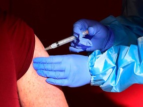 A senior citizen receives a COVID-19 vaccine at the Corona High School gymnasium in the Riverside County city of Corona, California on January 15, 2021, a day after California began offering the coronavirus vaccine to residents 65 and older.