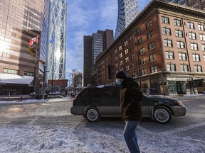 A masked pedestrian walks in downtown Calgary on Wednesday, February 3, 2021.