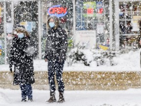 Masked Pedestrians wait to cross 17 Avenue S.W. as a heavy snow falls in Calgary on Friday, February 5, 2021. Azin Ghaffari/Postmedia