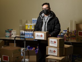 Charlie Luong, customer relations with Centre for Newcomers, poses for a photo with some of the packages that will be delivered to newcomers and vulnerable households during the COVID-19 pandemic on Sunday, February 7, 2021. Azin Ghaffari/Postmedia