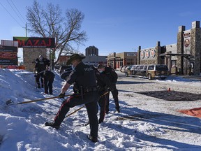 Members of Calgary Police Services rake the snow for evidence at the scene of a suspicious death at the parking lot of Mazaj Lounge and Restaurant on Macleod Trail on Saturday, February 20, 2021.