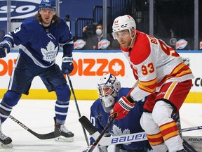 TORONTO, ON - FEBRUARY 22:  Sam Bennett #93 of the Calgary Flames looks for a puck to tip over Michael Hutchinson #30 of the Toronto Maple Leafs during an NHL game at Scotiabank Arena on February 22, 2021 in Toronto, Ontario, Canada.