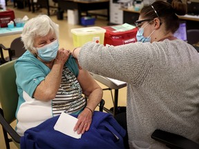 Mary House, 80, receives the COVID-19 vaccine from Alyssa Zaderey in Calgary on Wednesday, Feb. 24, 2021.