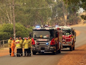 A state emergency worker (2nd L) talks to a fire crew as they head to fight a fire burning on a ridge being driven by strong winds in the suburb of Brigadoon in Perth on Feb. 2, 2021, just days after the west coast city entered a coronavirus lockdown.