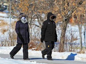 Walkers bundled up to stay warm while walking along the Bow River pathway as the extreme cold continued in Calgary on Sunday, Feb. 14, 2021.