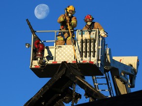 The moon sets behind Calgary firefighters as they deal with the aftermath of a fire that destroyed at least one and damaged several other homes on Nolanfield Lane in Nolan Hill in the early hours of Thursday, December 3, 2020.