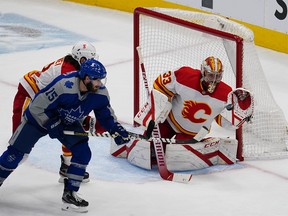 Feb. 24, 2021; Toronto, Ontario, CAN; Calgary Flames goaltender David Rittich (33) makes a glove save as Toronto Maple Leafs forward Alexander Kerfoot (15) attempts the deflection during the second period at Scotiabank Arena.