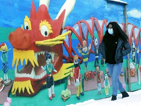 Jenny Wu walks by a mural in Chinatown as celebrations to celebrate the Lunar New Year will be limited due to COVID in Calgary on Thursday, Feb. 11, 2021.
